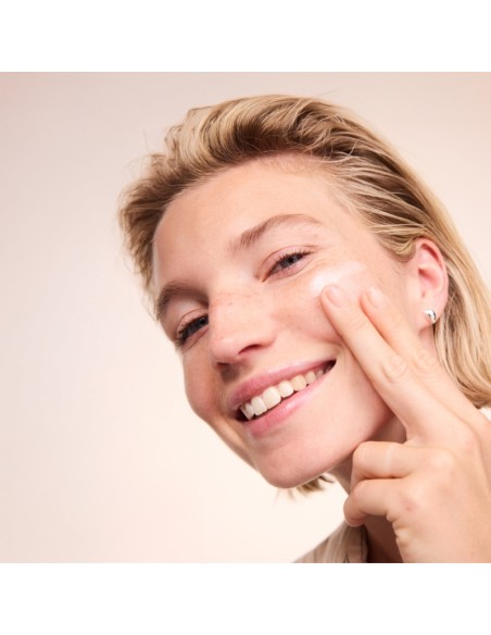Mujer aplicando la leche limpiadora Basis Sensitive Aloe y Karité de Lavera sobre la piel del rostro.